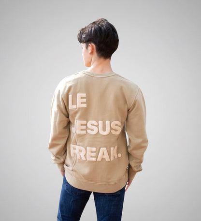 Person wearing a beige sweatshirt with text in a forest