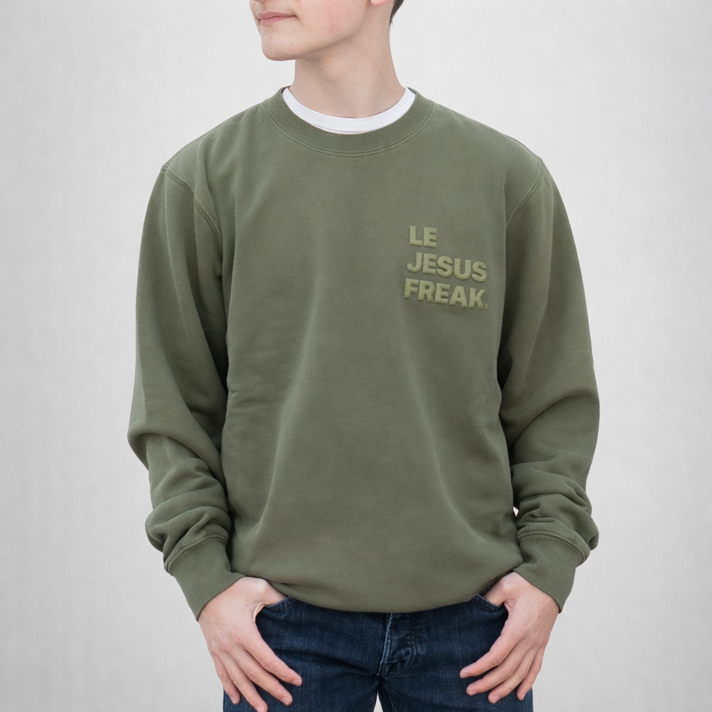 Person wearing a green sweatshirt with 'LE JESUS FREAK' text on a plain background