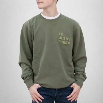 Person wearing a green sweatshirt with 'LE JESUS FREAK' text on a plain background