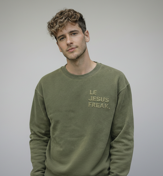 Man wearing a green sweatshirt with 'LE JESUS FREAK' text on a plain background